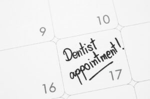 The words "dentist appointment" written on a calendar as a reminder about a teeth cleaning.