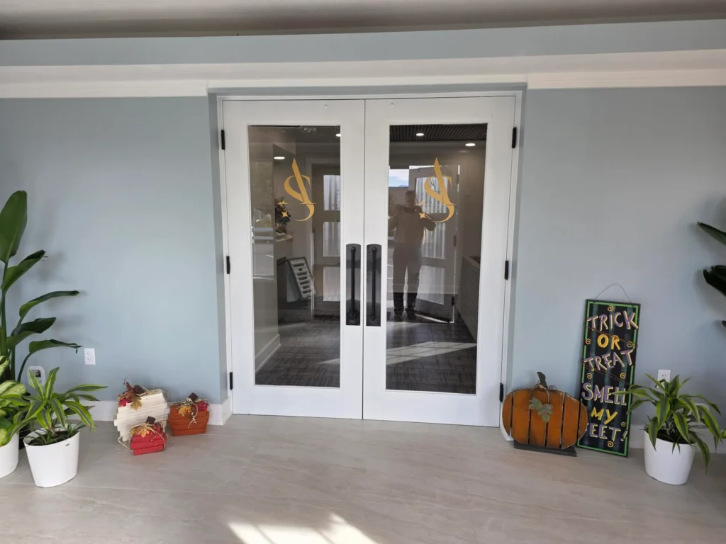 Glass entry doors with the Angel's Smile logo, seen from inside the office